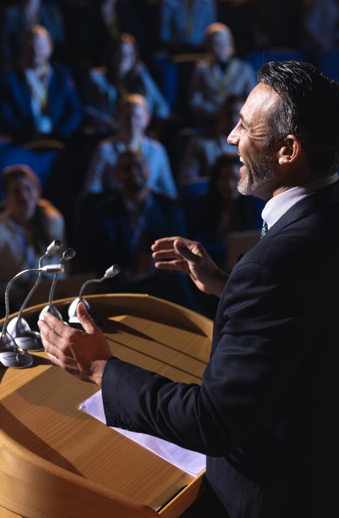 side-view-of-caucasian-businessman-standing-and-giving-presentation-in-the-auditorium-q1t3qmwuqs6k4exu26476iqqt9ixdykbvozbfld1ts